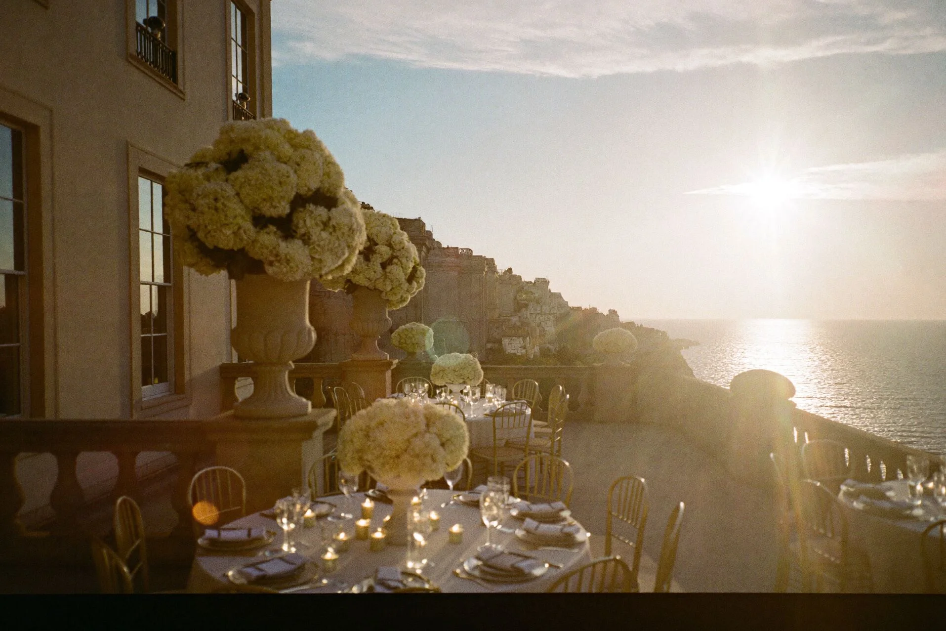 Terrasse de villa face à la mer au coucher du soleil, tables dressées